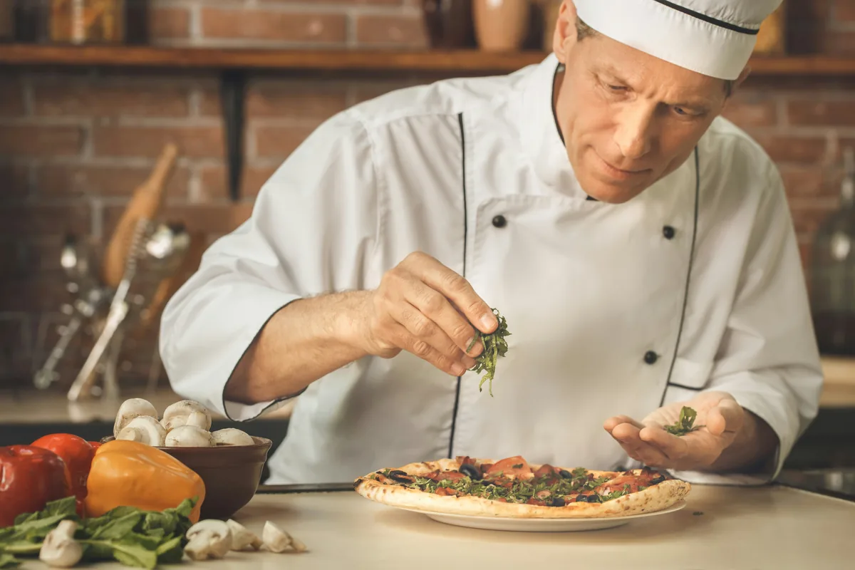 Private chef garnishing a dish in a warm kitchen