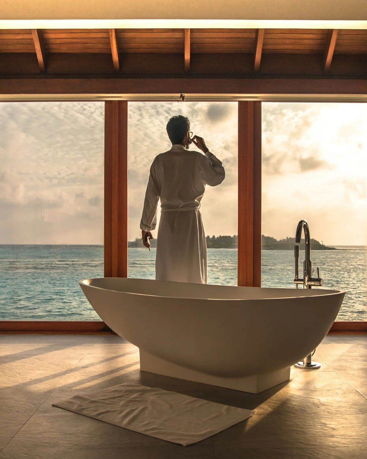 Ocean-facing bathroom with freestanding bathtub at sunset