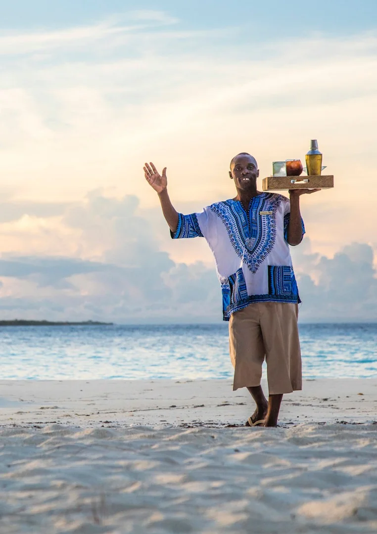 Beach butler carrying welcome drinks by the ocean